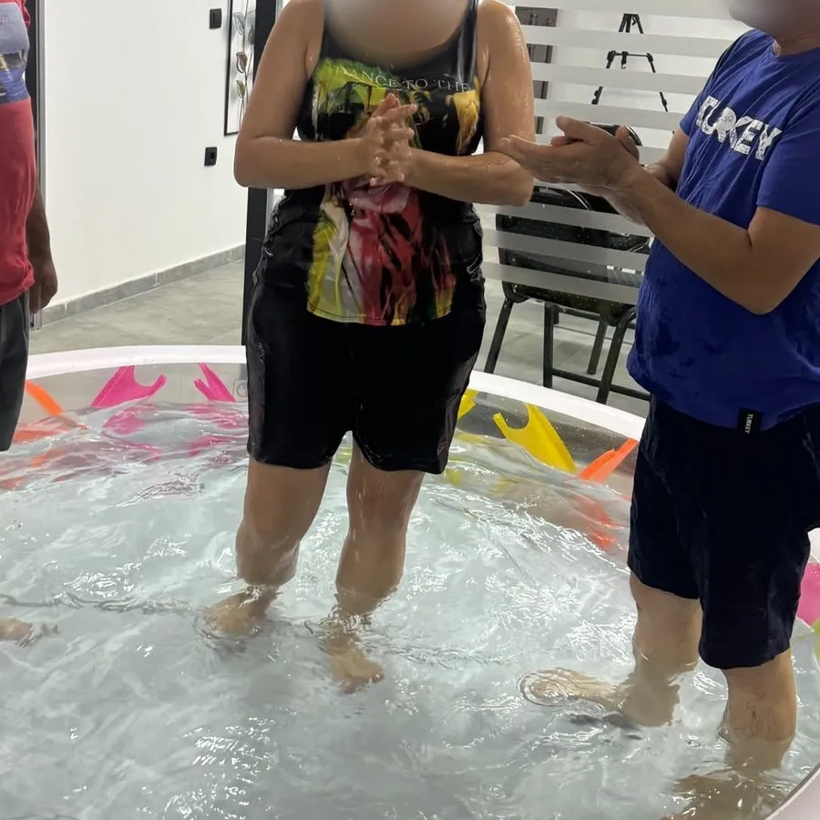 A new believer in the baptism pool, hands folded in prayer