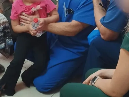 A doctor holding a little girl during a health screening